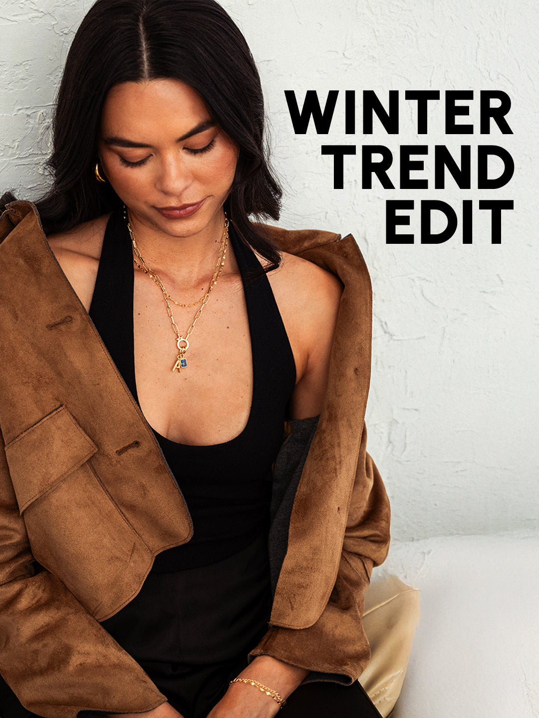 Woman wearing a brown jacket over a black top with 'Winter Trend Edit' text on a white background