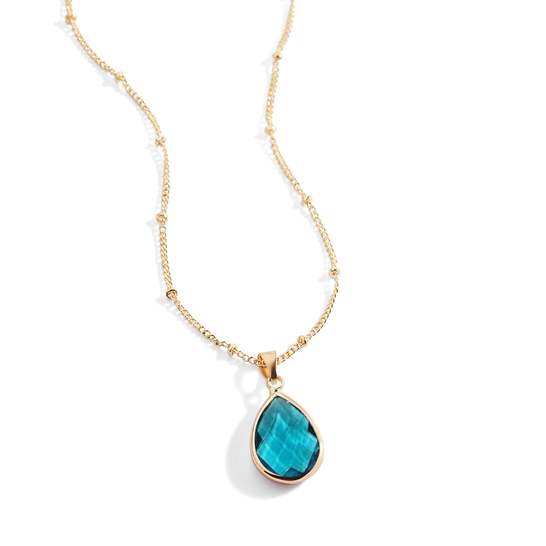 Gold necklace with a green teardrop pendant on a white background