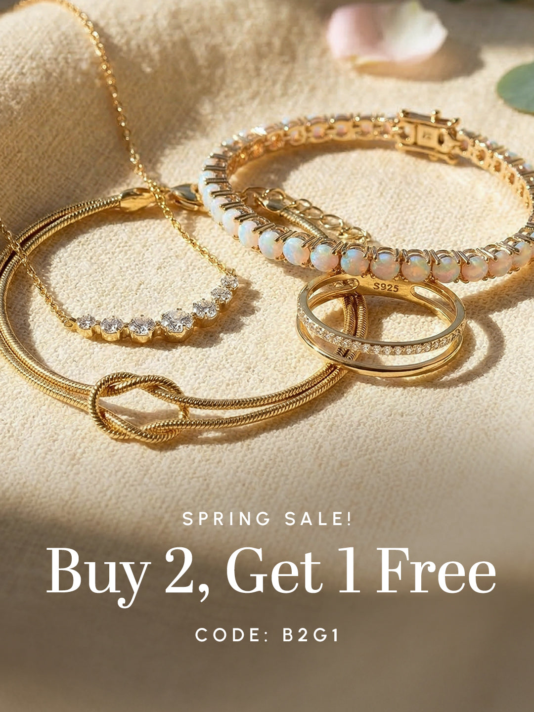Close-up of gold jewelry including bracelets, rings, and necklace with text ‘Spring Sale Buy 2, Get 1 Free’ and code B2G1.