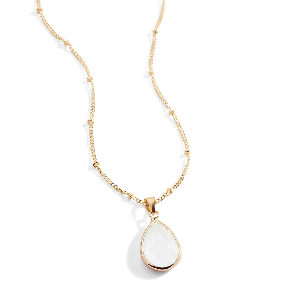 Gold necklace with a white teardrop pendant on a light gray background