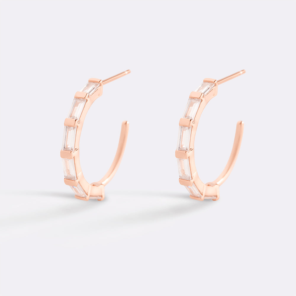 Rose gold hoop earrings on a light gray background