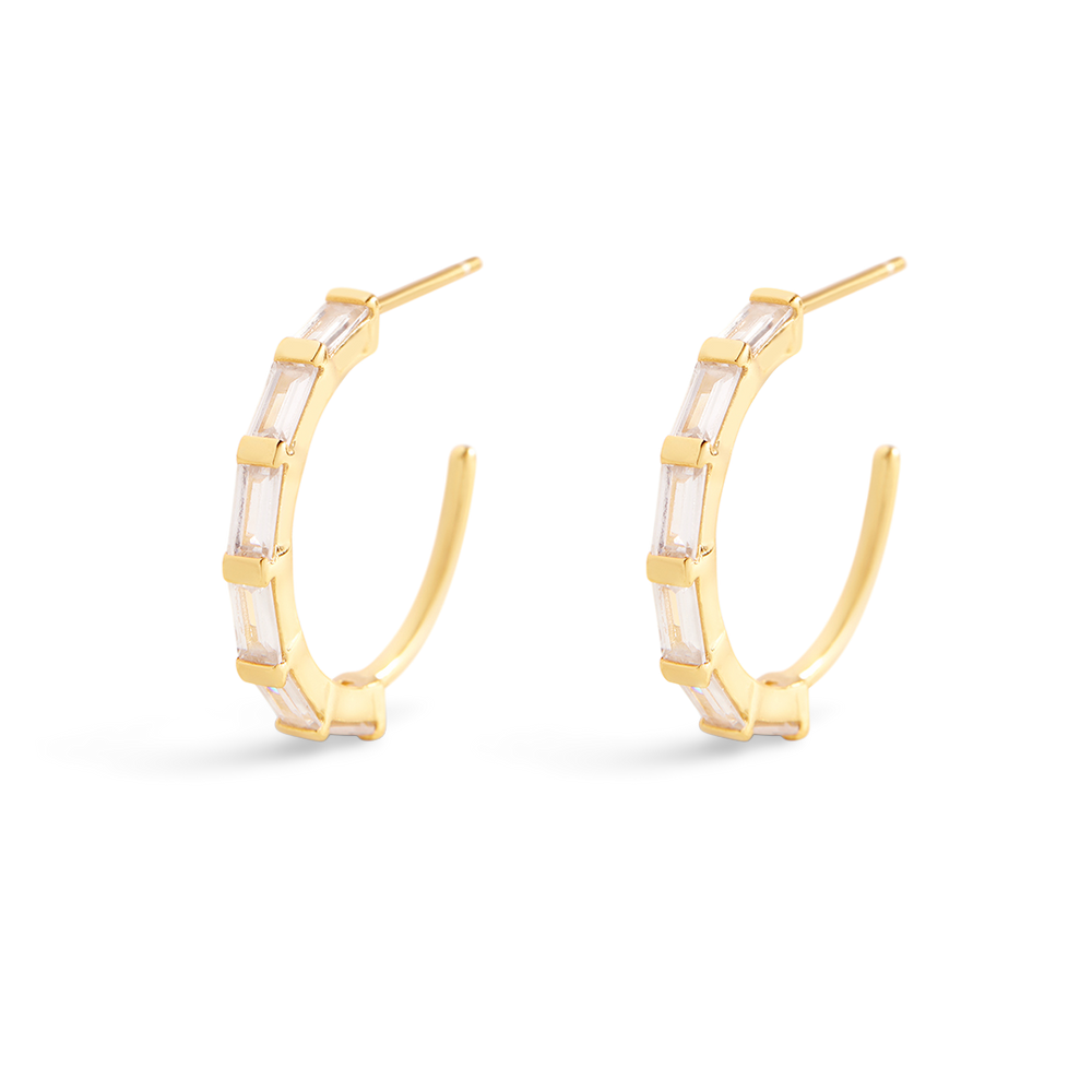 Gold hoop earrings with a white stone on a light gray background