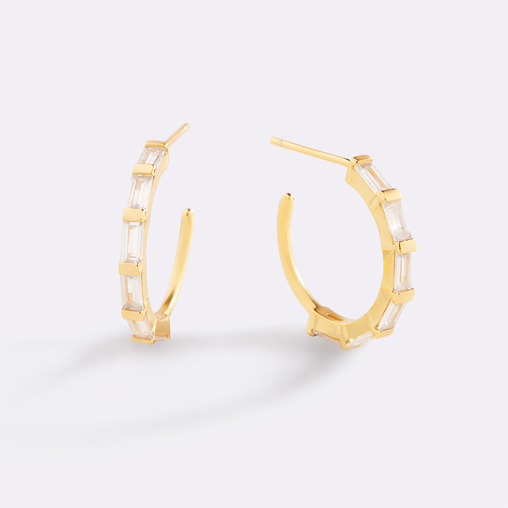 Gold hoop earrings with clear gemstones on a white background