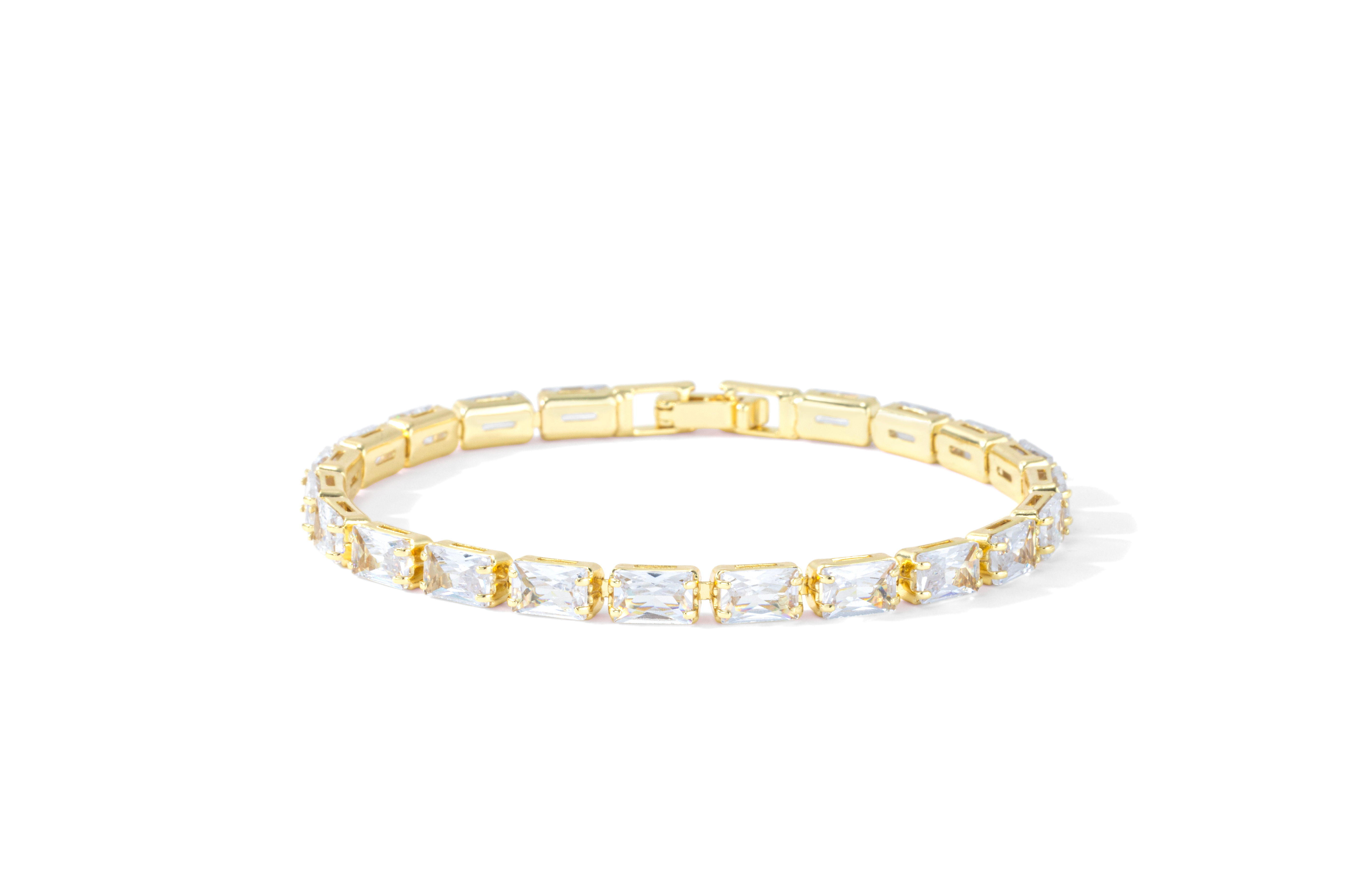 Gold baguette tennis bracelet with cubic zirconia stones on a white background