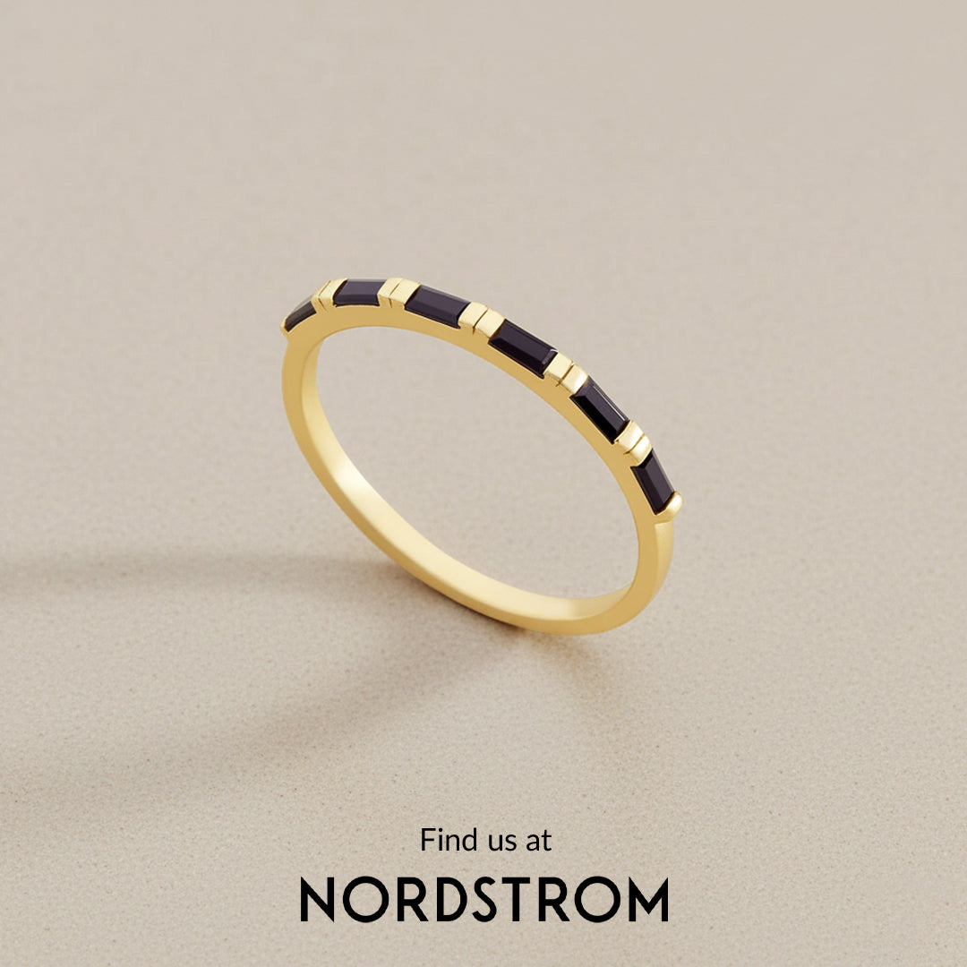 Gold ring with black stones on a beige background, Nordstrom branding visible.