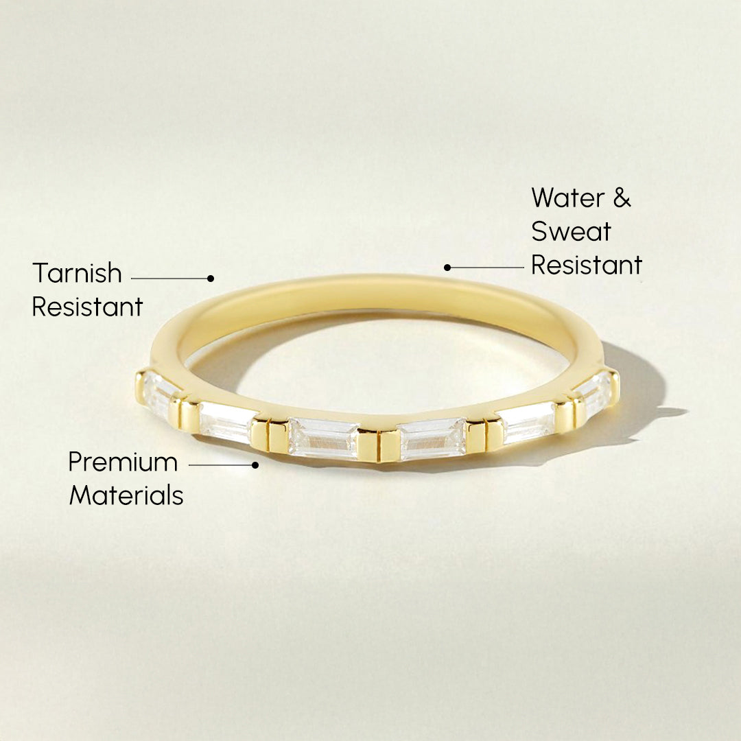 Gold ring with baguette diamonds on a light beige background, labeled for features.
