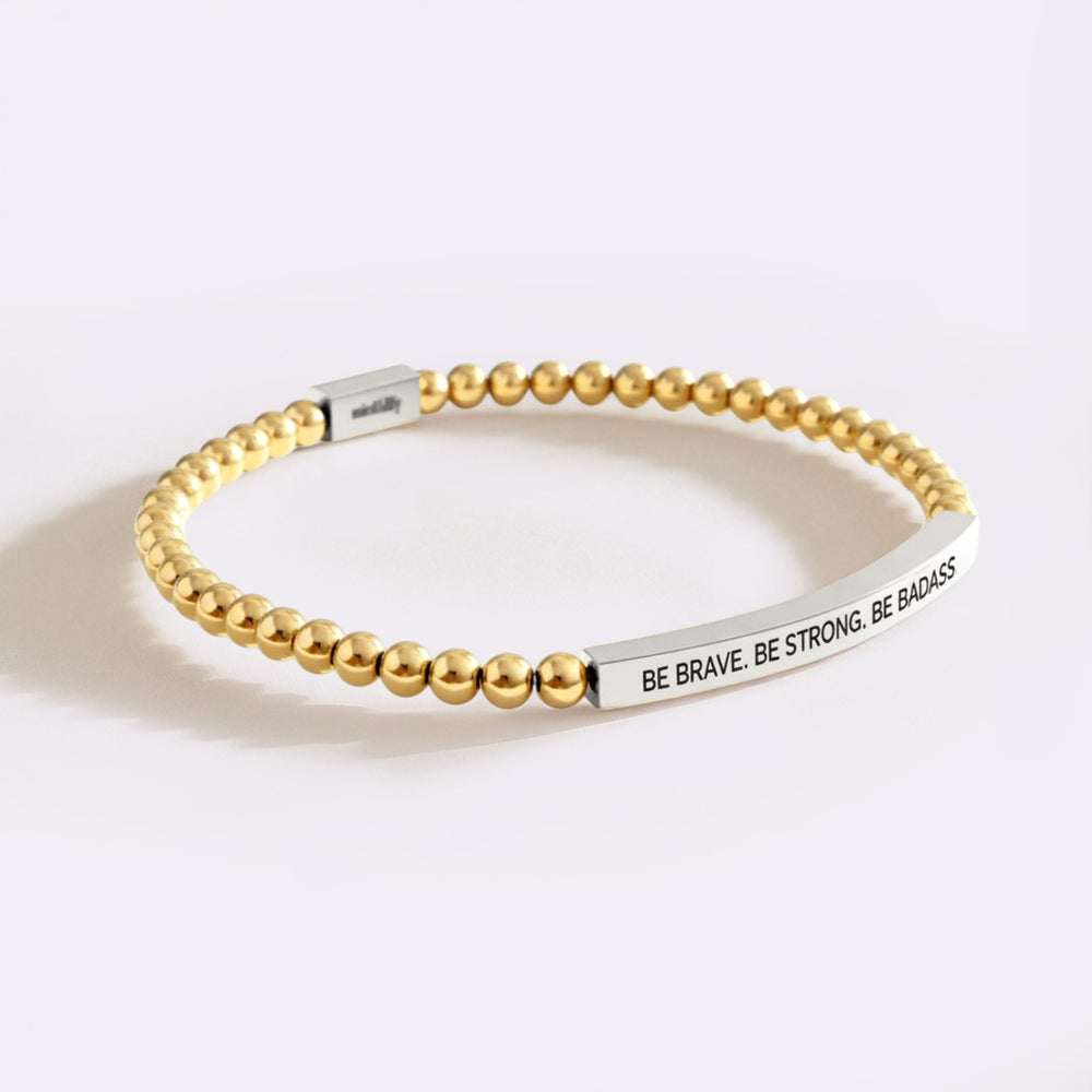 Gold beaded bracelet with motivational message on a white background