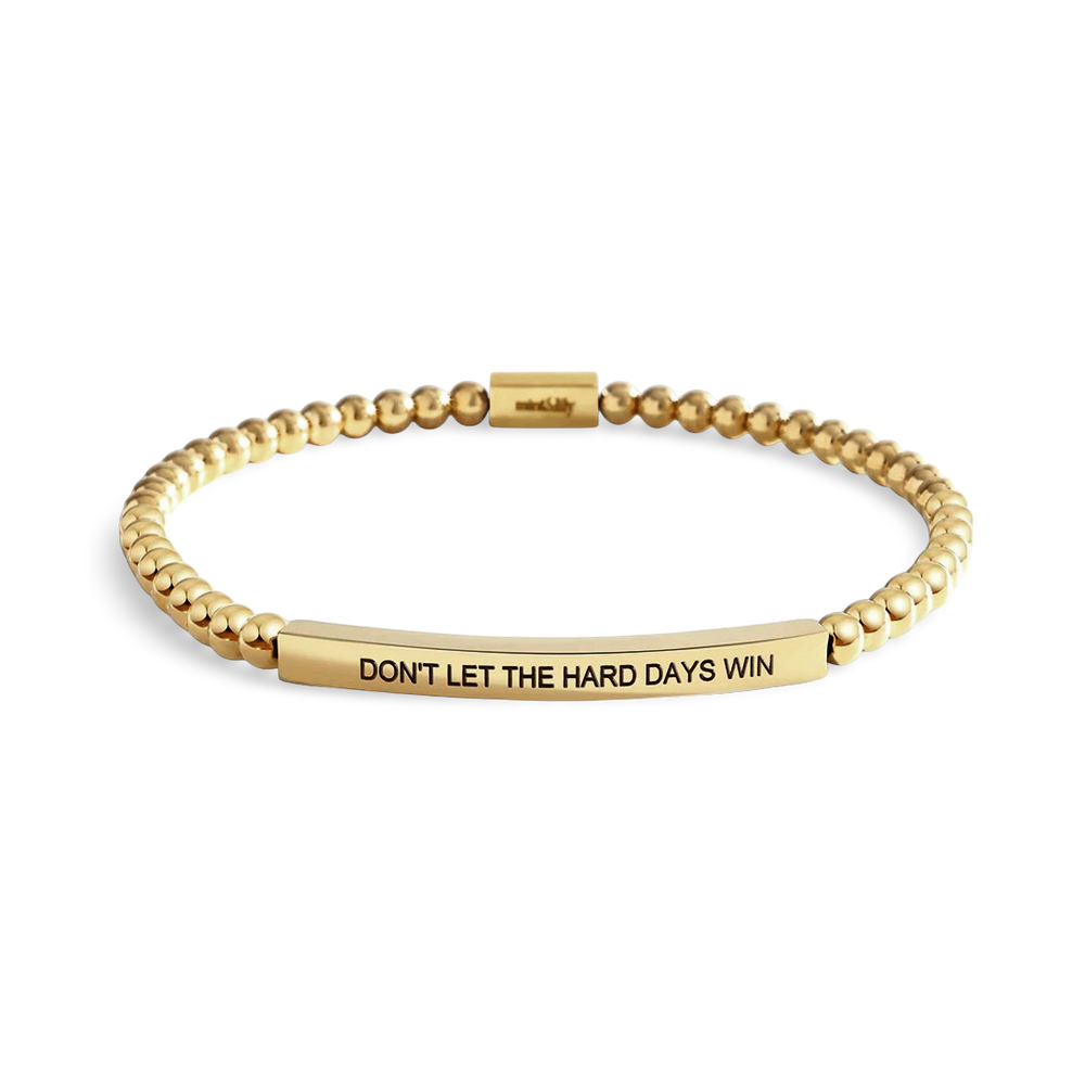 Gold beaded bracelet with motivational message on a light background