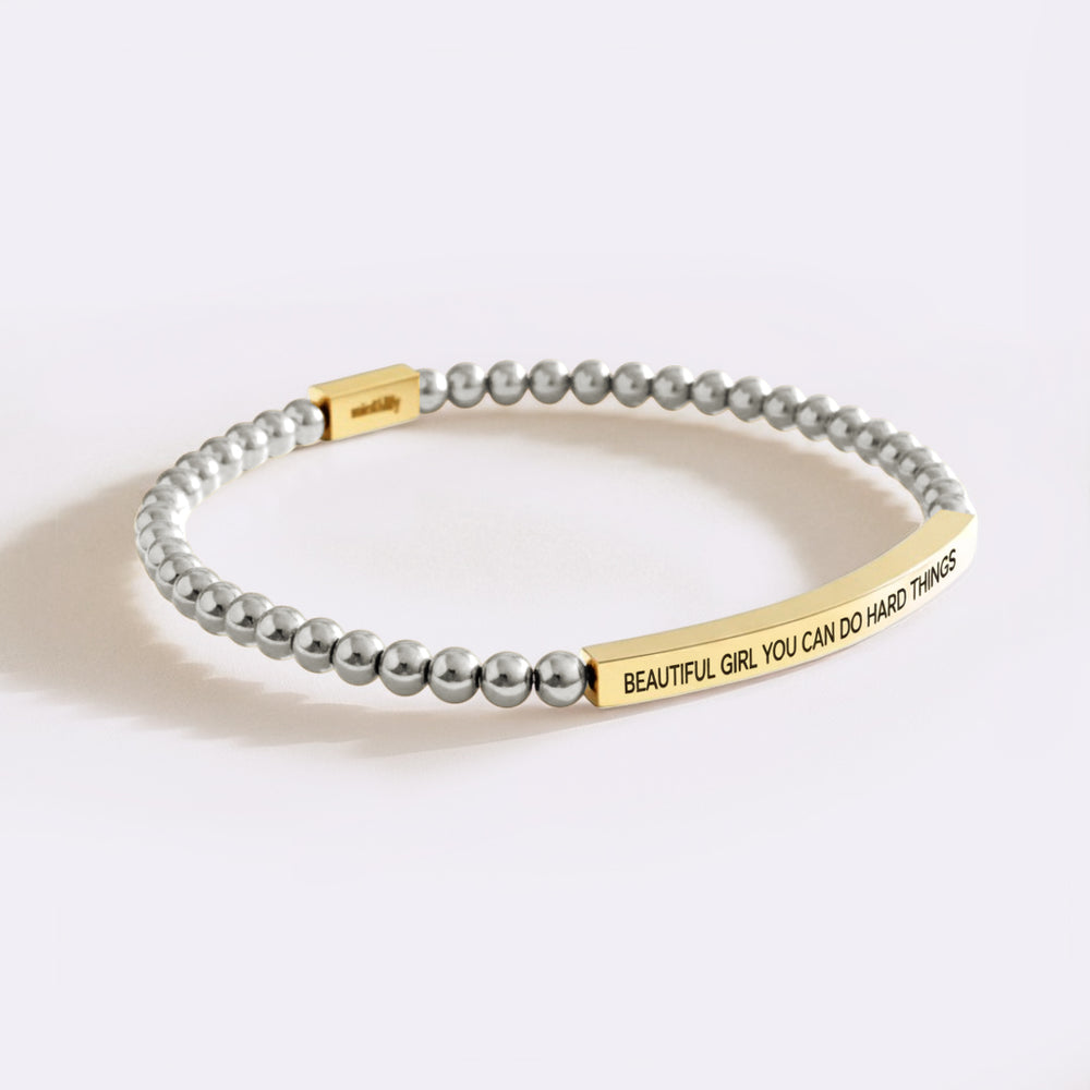 Bracelet with gray beads and gold tag on a white background