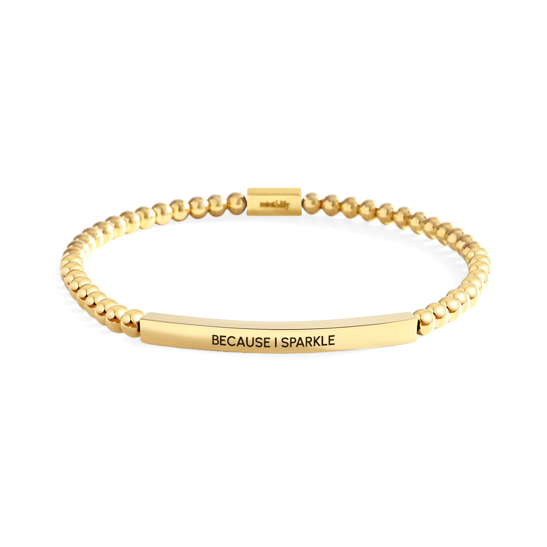 Gold bracelet with 'BECAUSE I SPARKLE' text on a white background