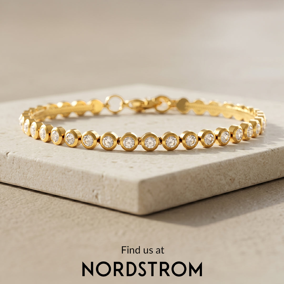 Gold bracelet with clear stones on a beige surface, Nordstrom branding visible.