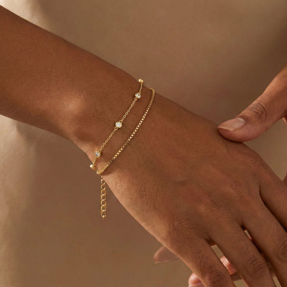 Gold bracelet on a wrist against a neutral background