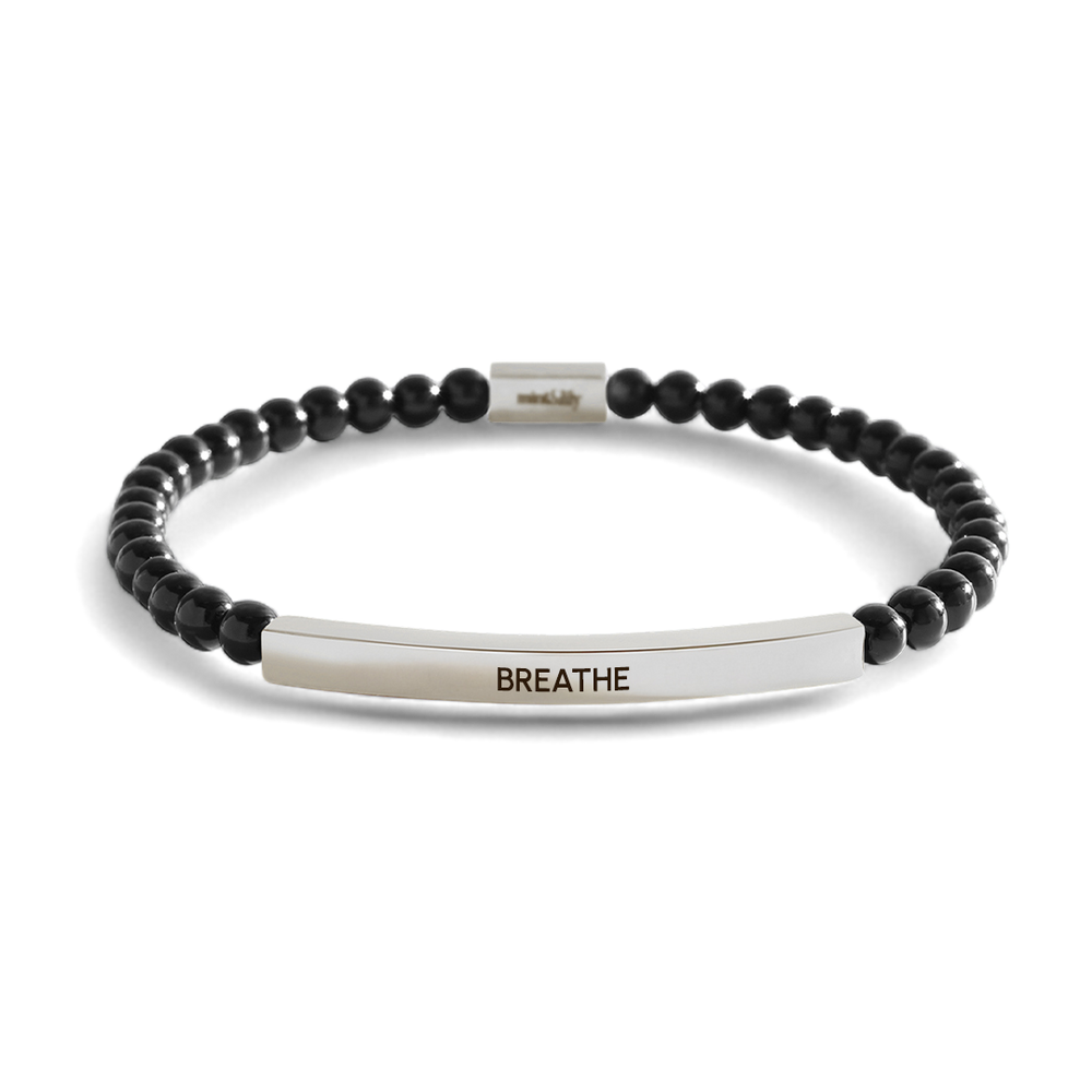 Black beaded bracelet with a silver bar featuring the word 'BREATHE' on a light gray background