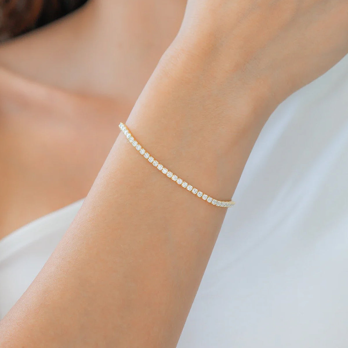 Delicate gold bracelet on a wrist against a neutral background