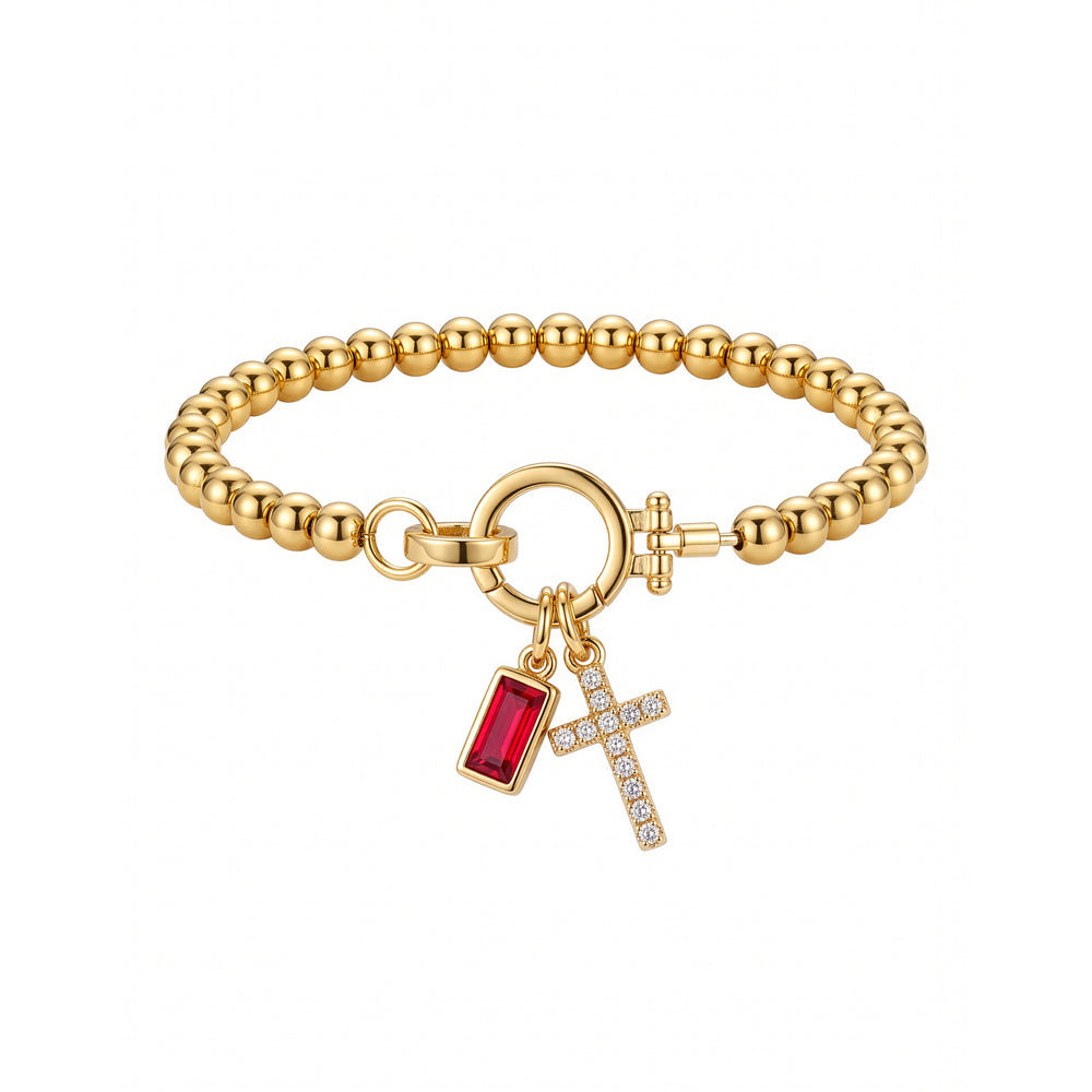 Flat lay of the Cross Charm Birthstone Bracelet with January garnet birthstone charm.