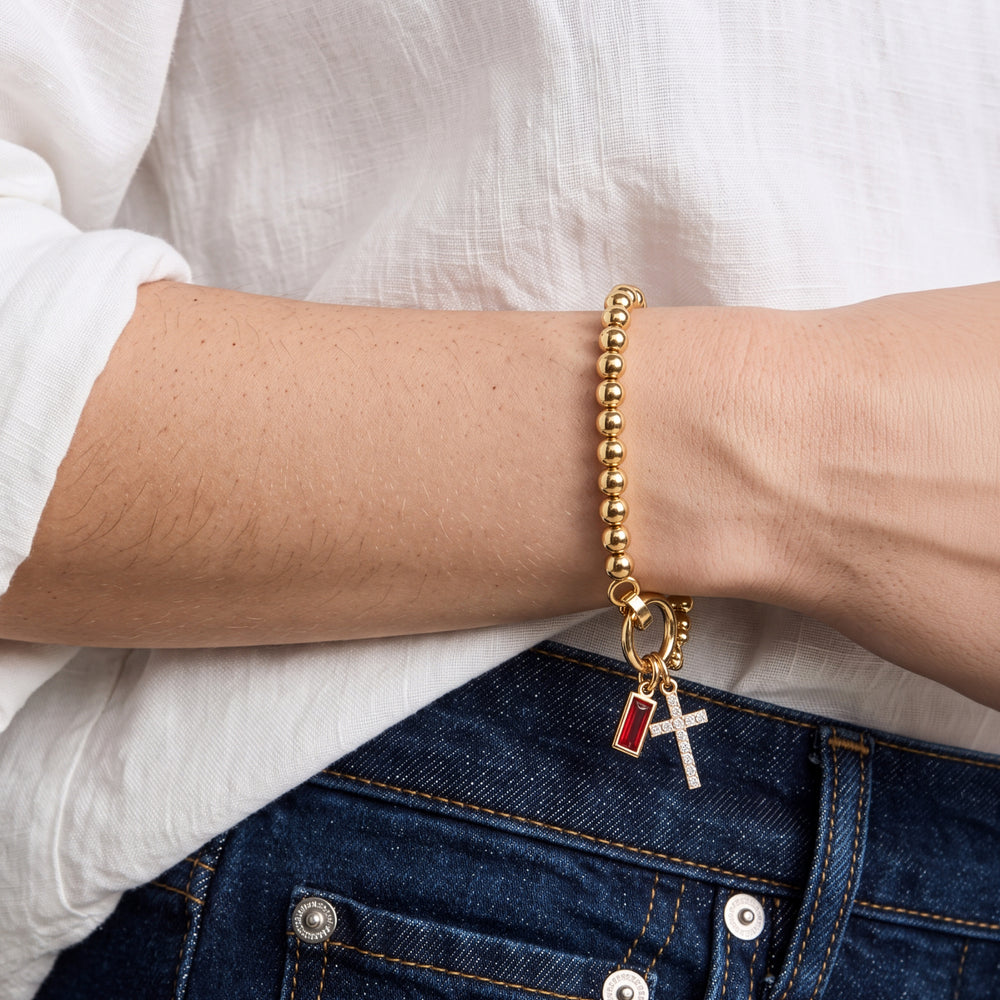 Model wearing the Cross Charm Birthstone Bracelet with January garnet birthstone charm on her wrist.