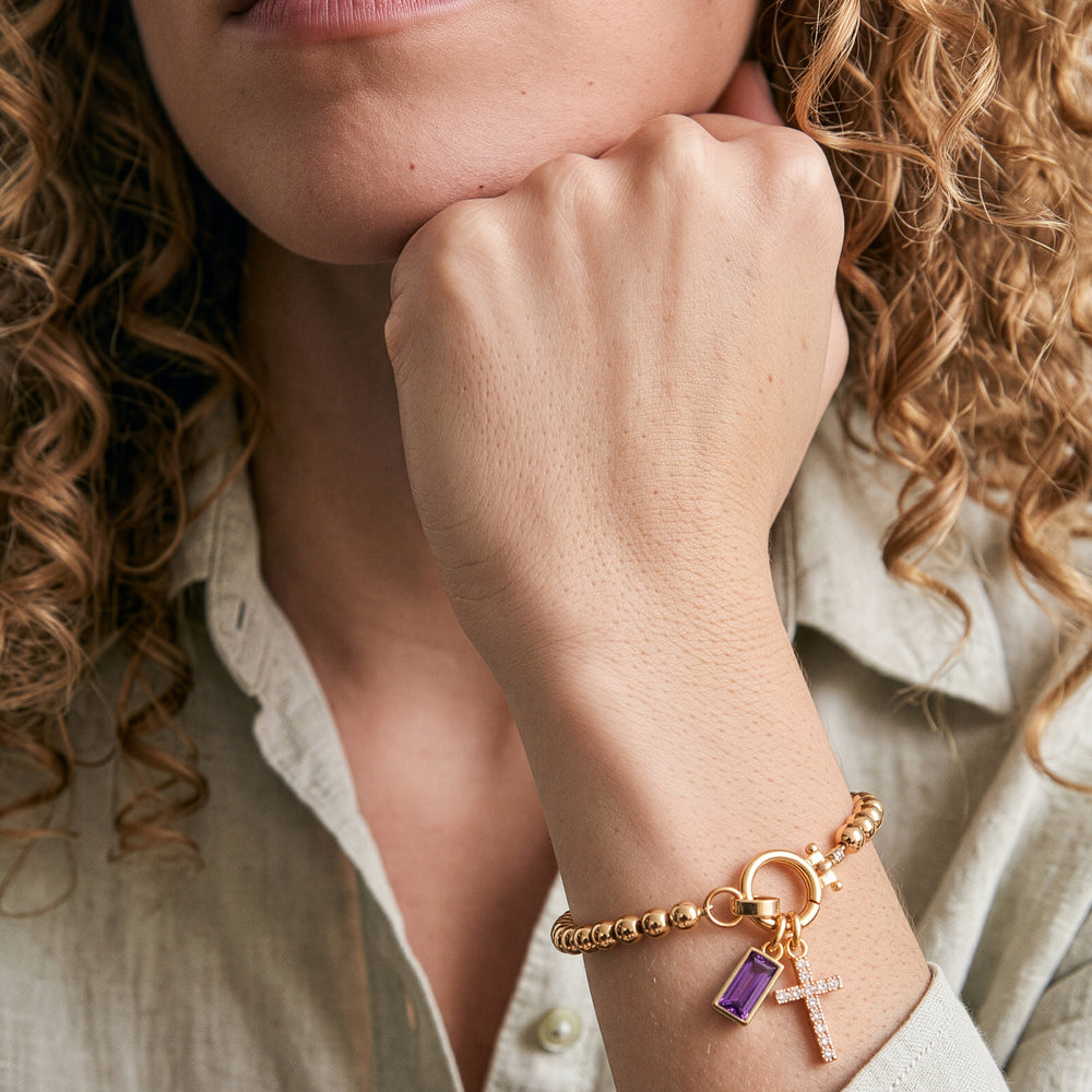 Model wearing the Cross Charm Birthstone Bracelet with June alexandrite birthstone charm on her wrist.