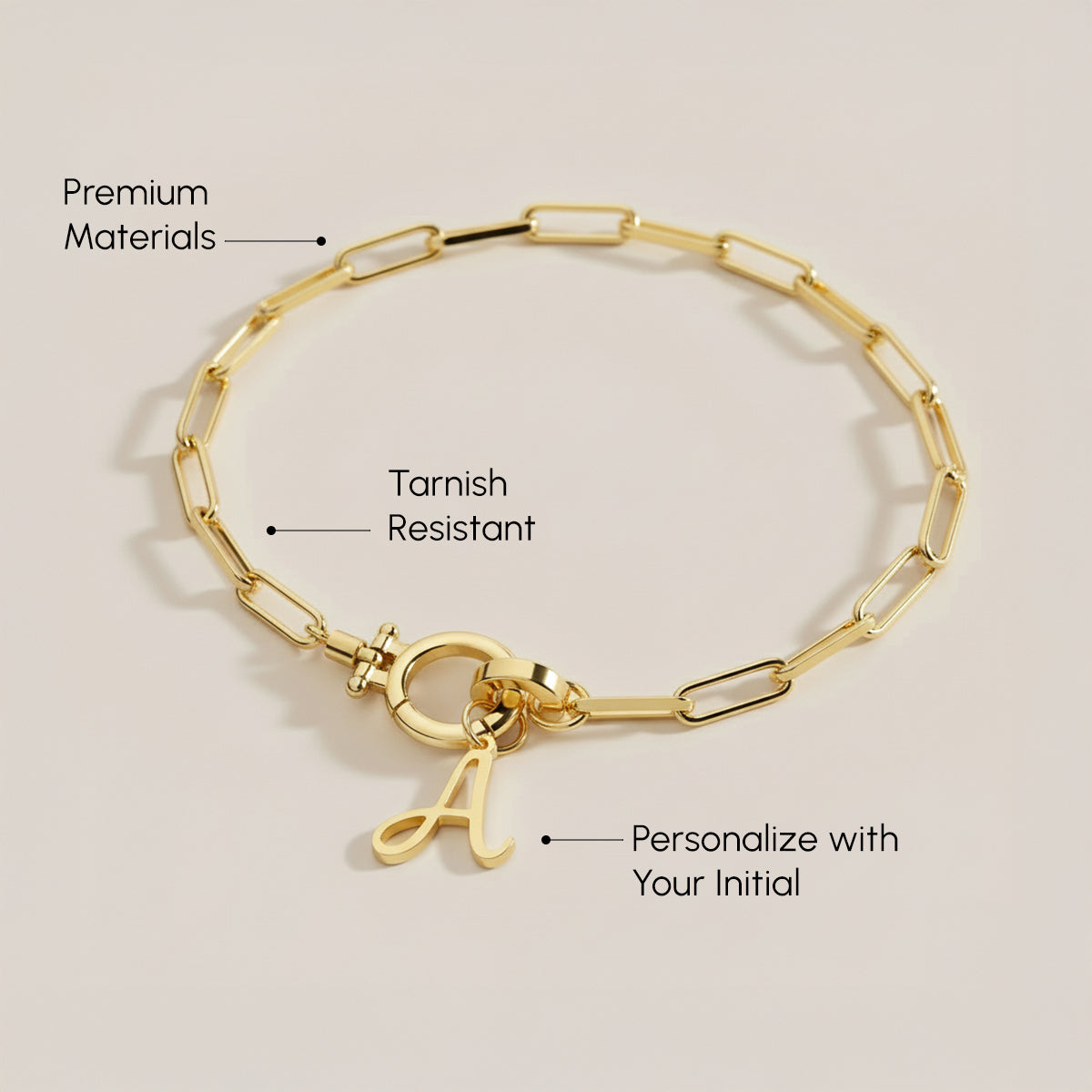 Gold bracelet with a clasp and 'L' charm on a beige background