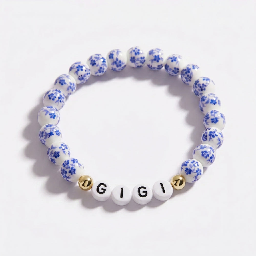 Bracelet with blue floral beads and 'GIGI' beads on a white background