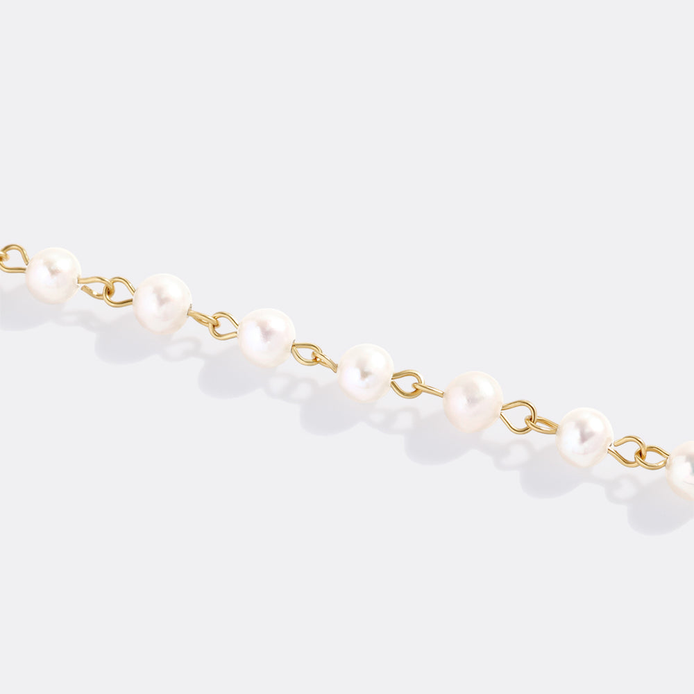 Pearl necklace with gold chain on a light gray background