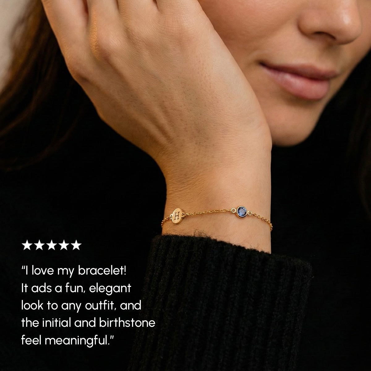 Person wearing a gold bracelet with a birthstone, set against a black background.