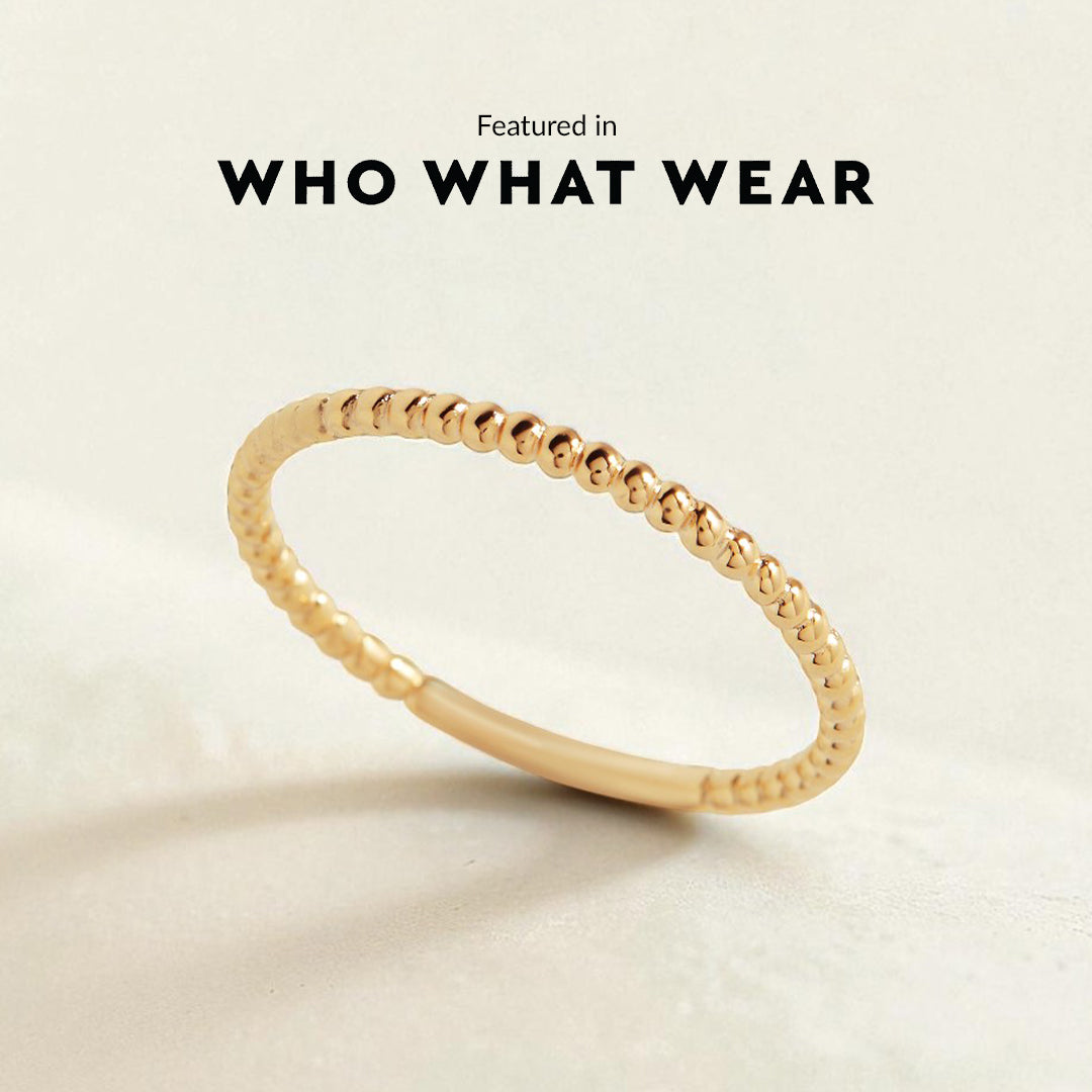 Gold ring on a beige background with 'WHO WHAT WEAR' text above.