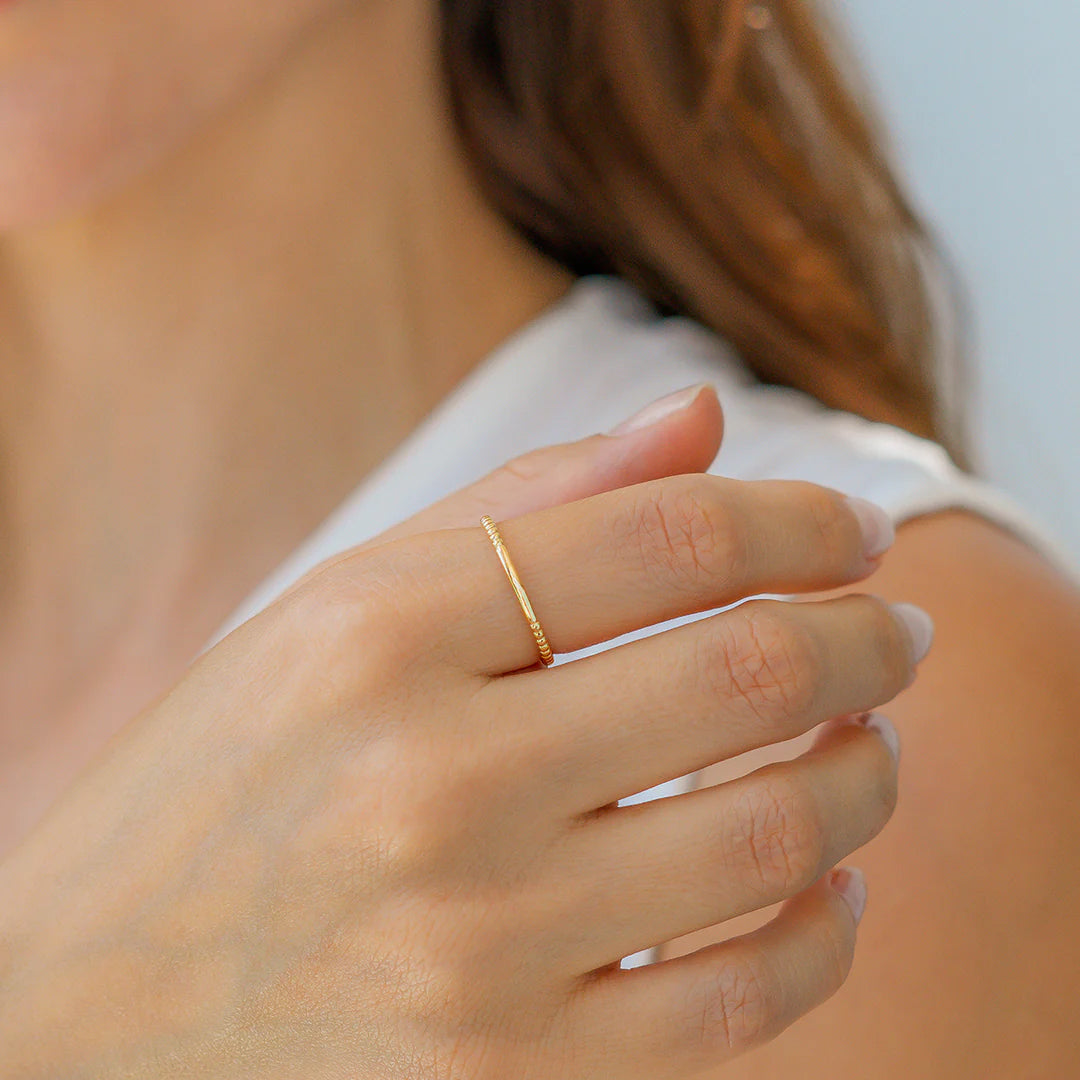 Close-up of a hand wearing a gold ring with a blurred background