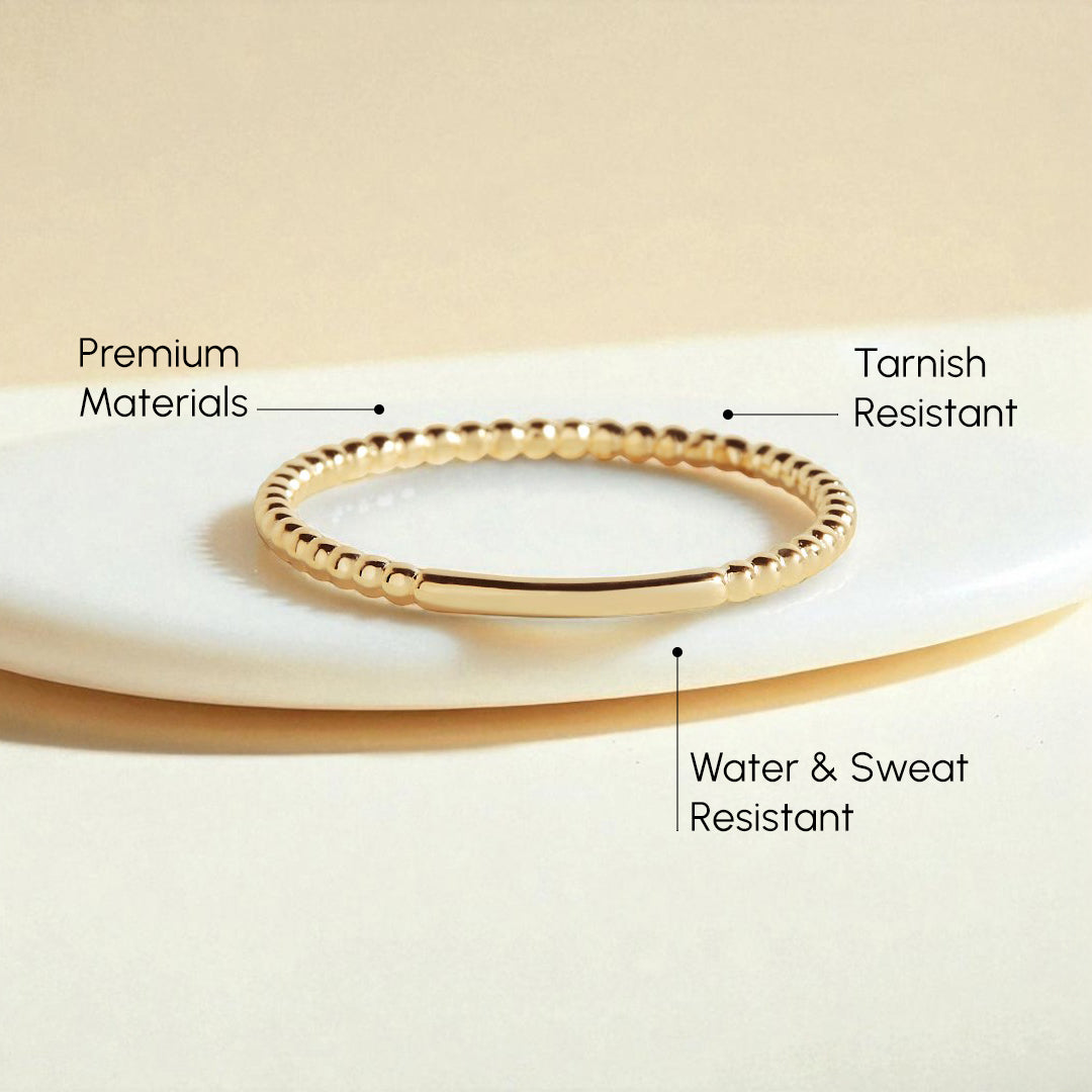 Gold ring on a beige surface with text highlighting features