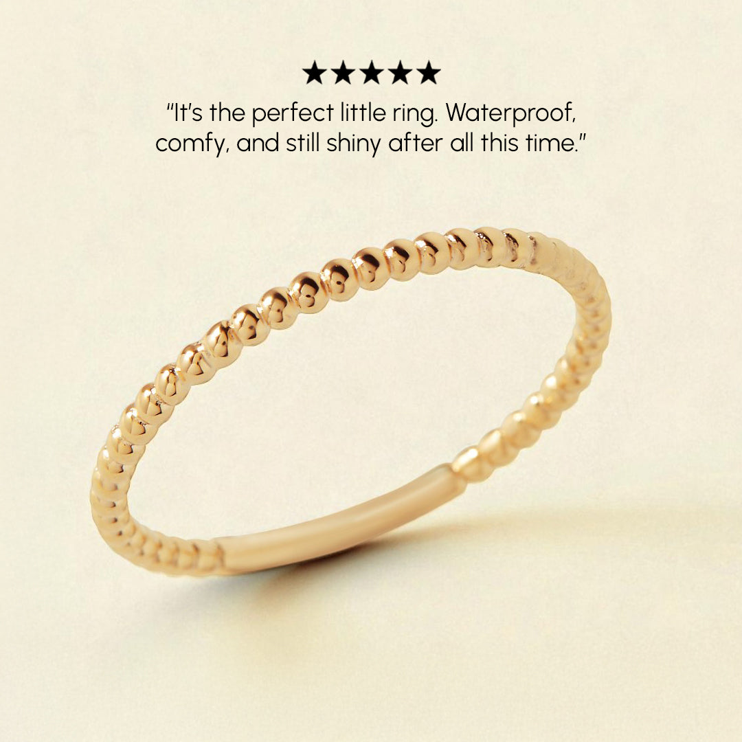 Gold ring on a beige background with text about its qualities