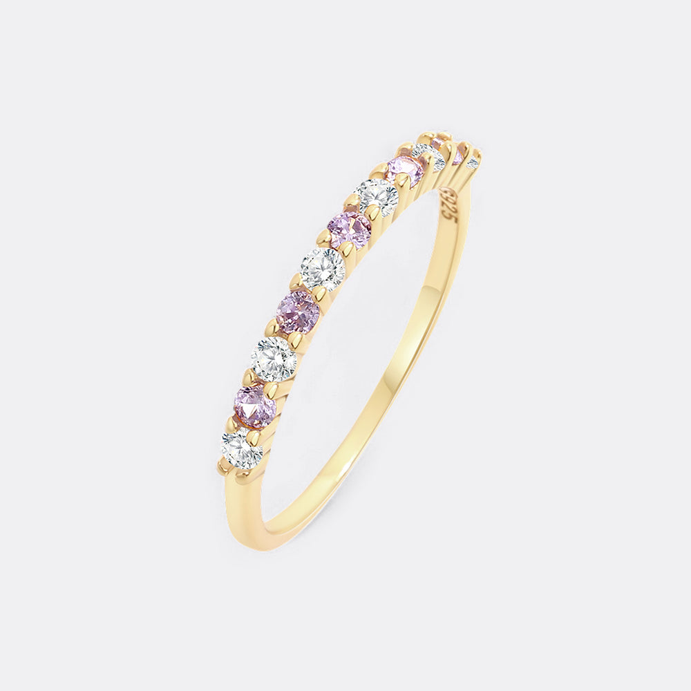 Gold ring with pink and clear gemstones on a light gray background