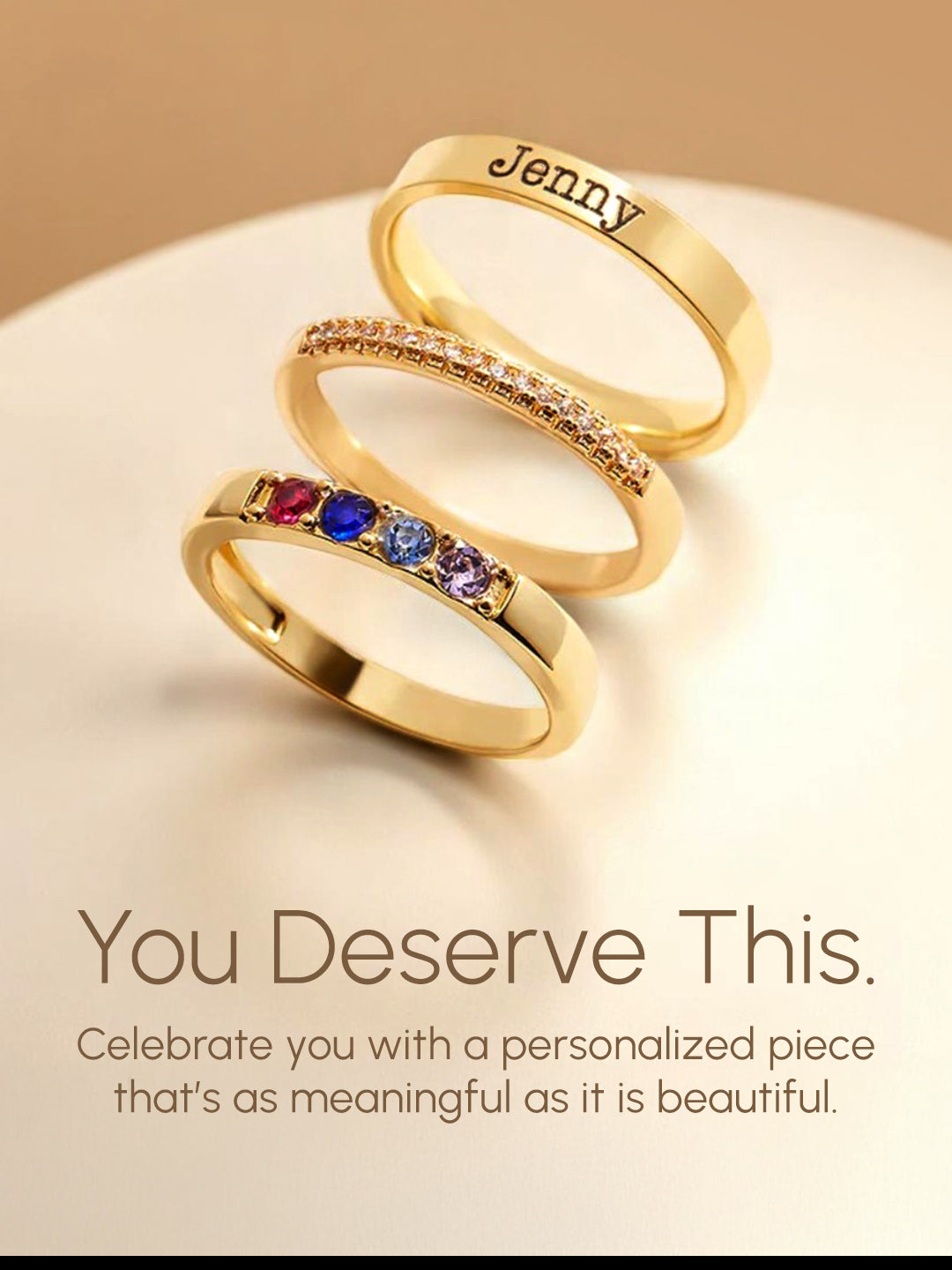 Two gold rings with engraved names on a beige background