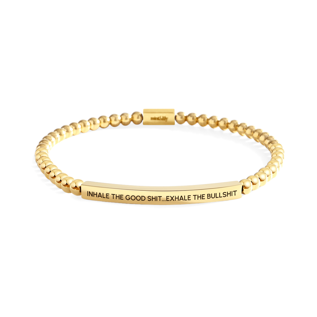 Gold beaded bracelet with engraved text on a white background