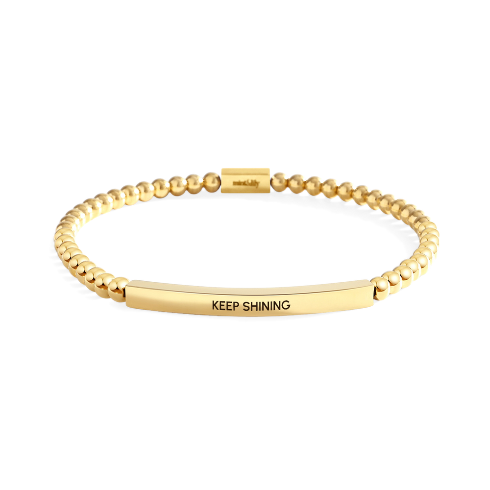Gold bracelet with 'KEEP SHINING' engraving on a white background