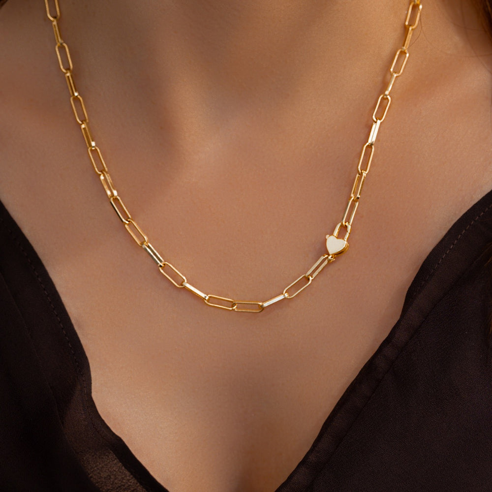 Gold chain necklace on a person wearing a black top