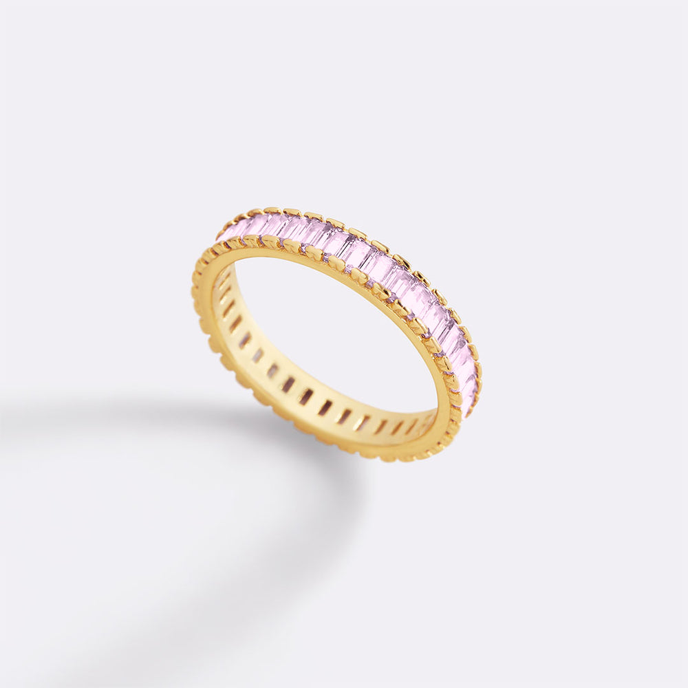 Gold ring with pink gemstones on a light gray background