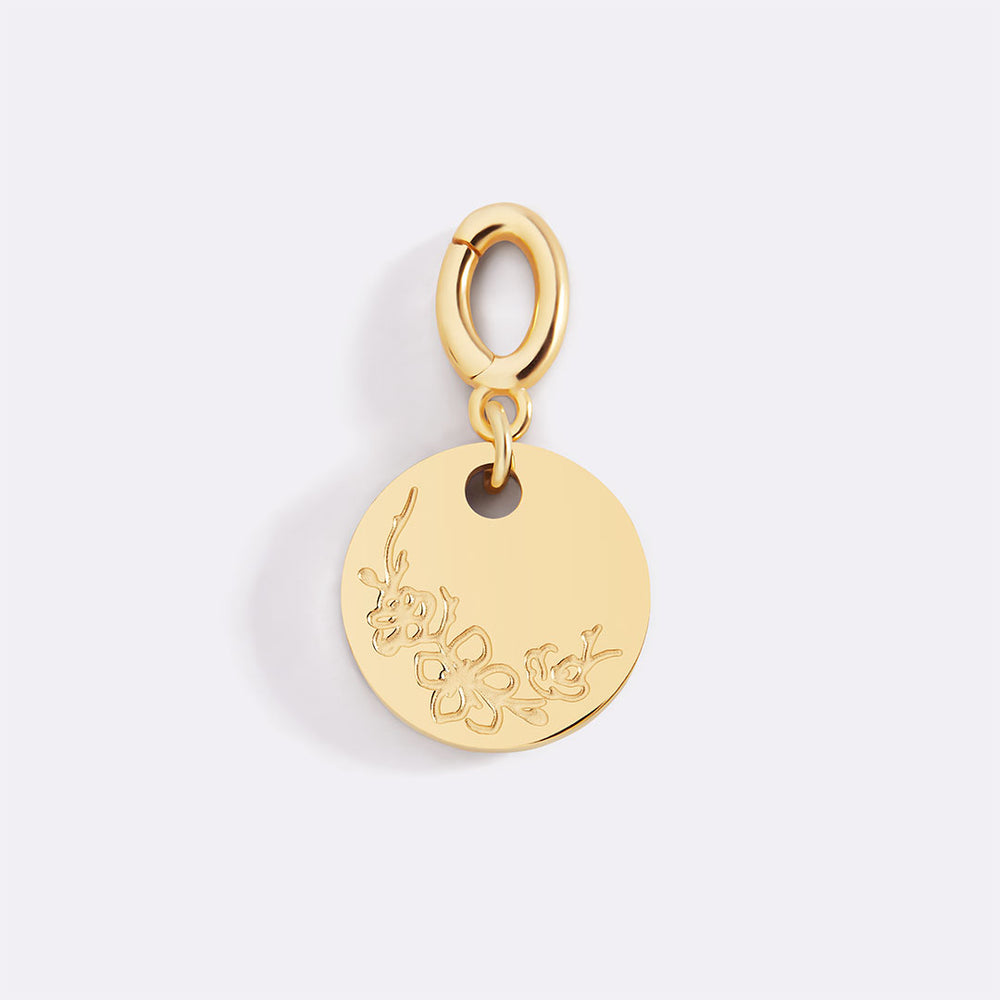 Gold pendant with engraved design on a light gray background