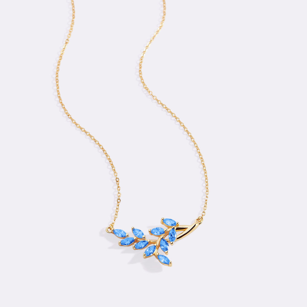 Gold necklace with blue gemstones on a light gray background
