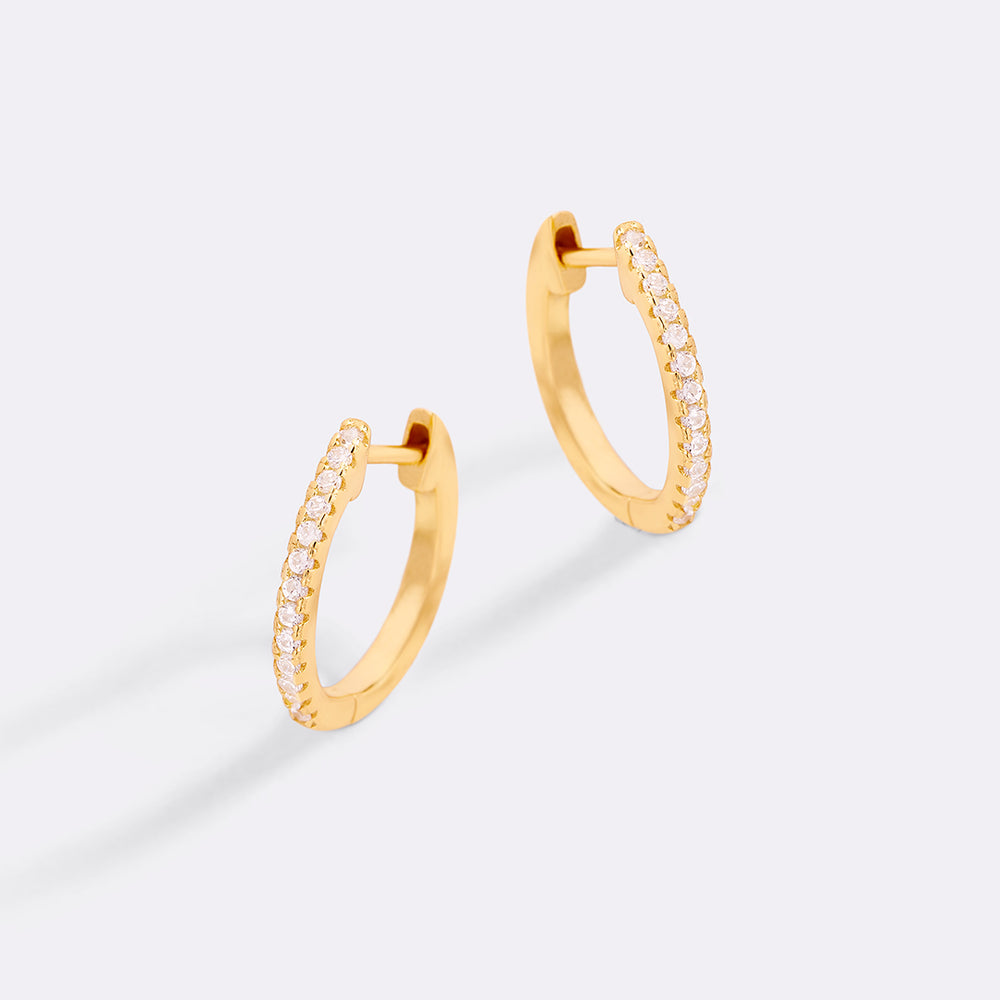 Gold hoop earrings with small diamonds on a light gray background