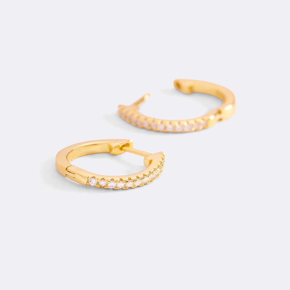 Two gold hoop earrings with small diamonds on a light gray background