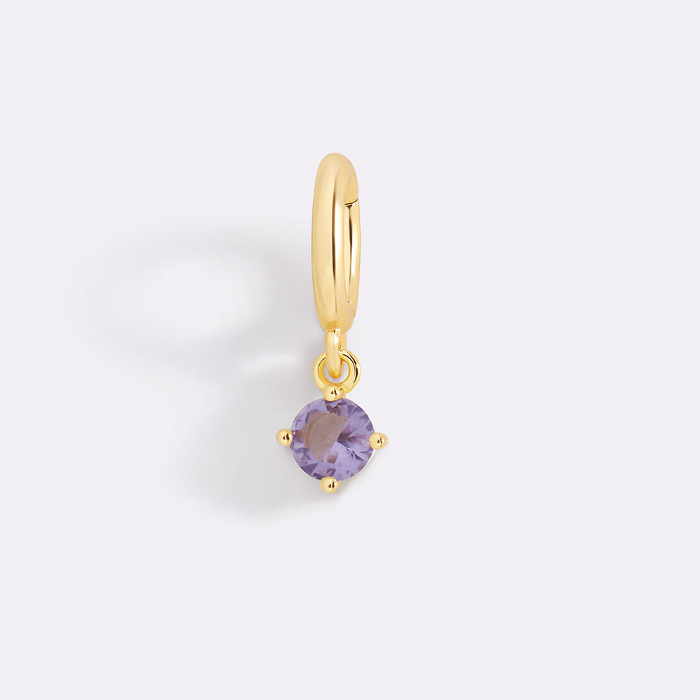 Gold earring with a purple gemstone on a light gray background