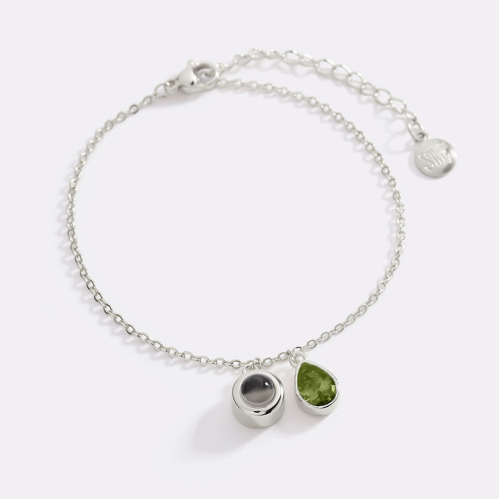 Silver bracelet with green gemstone on a white background