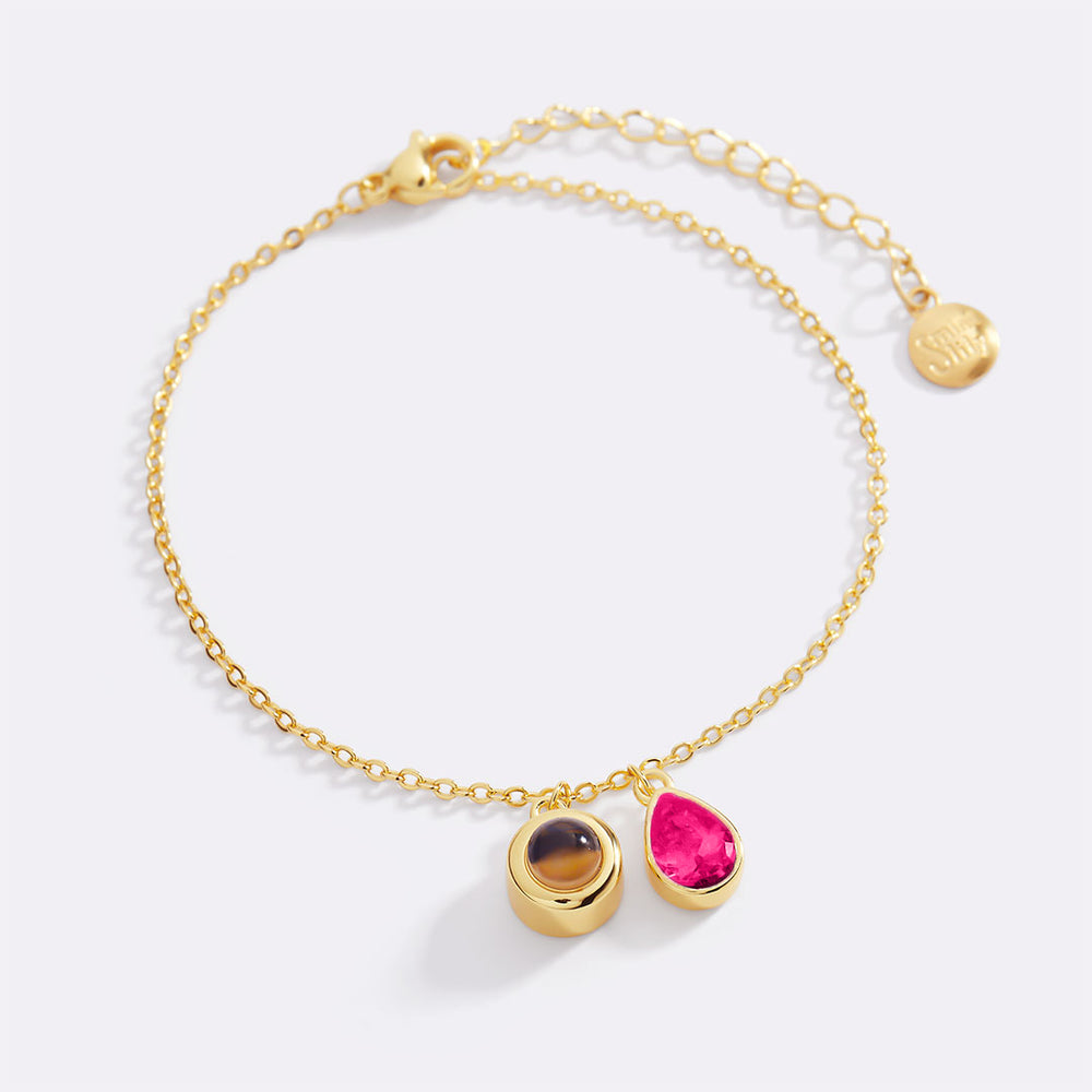 Gold bracelet with three gemstones on a white background