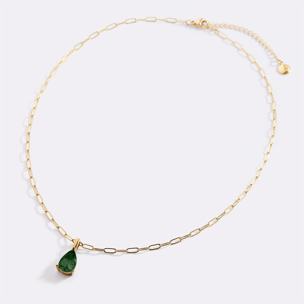 Gold necklace with a green teardrop pendant on a white background