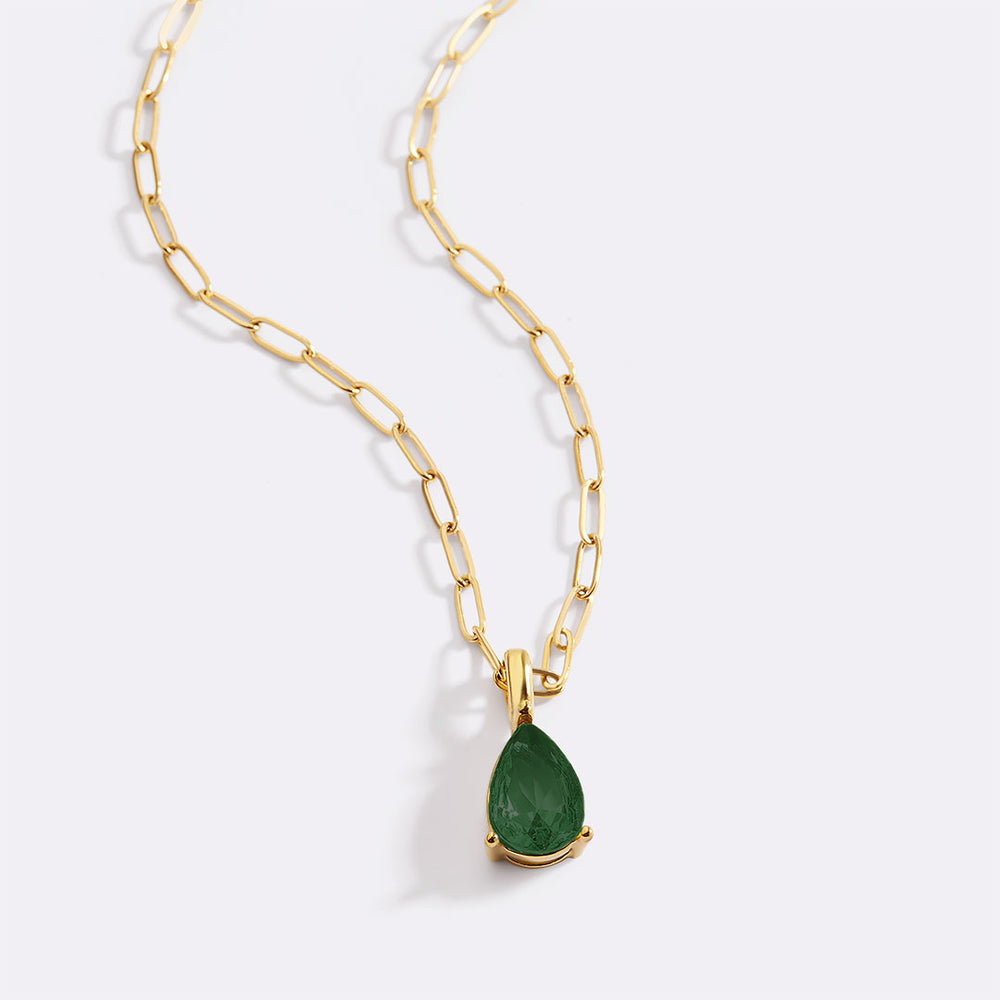 Gold necklace with a green teardrop pendant on a white background