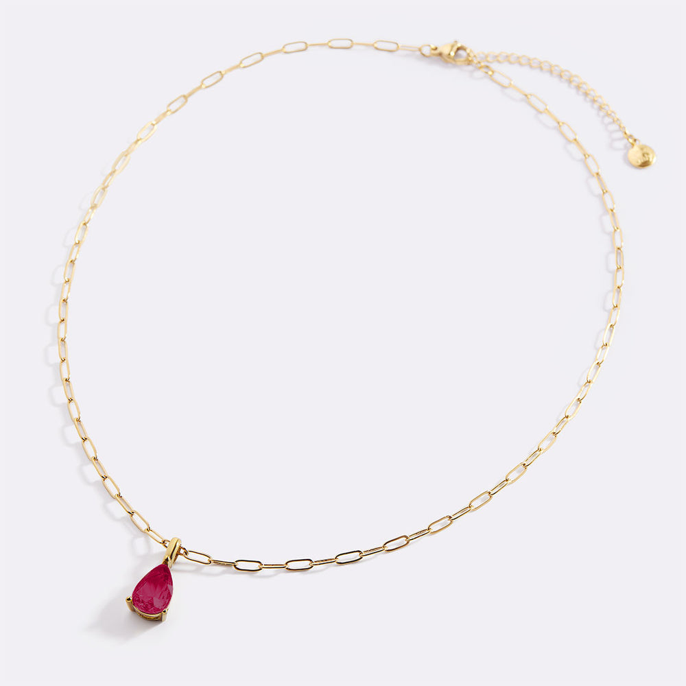Gold necklace with a red teardrop pendant on a white background
