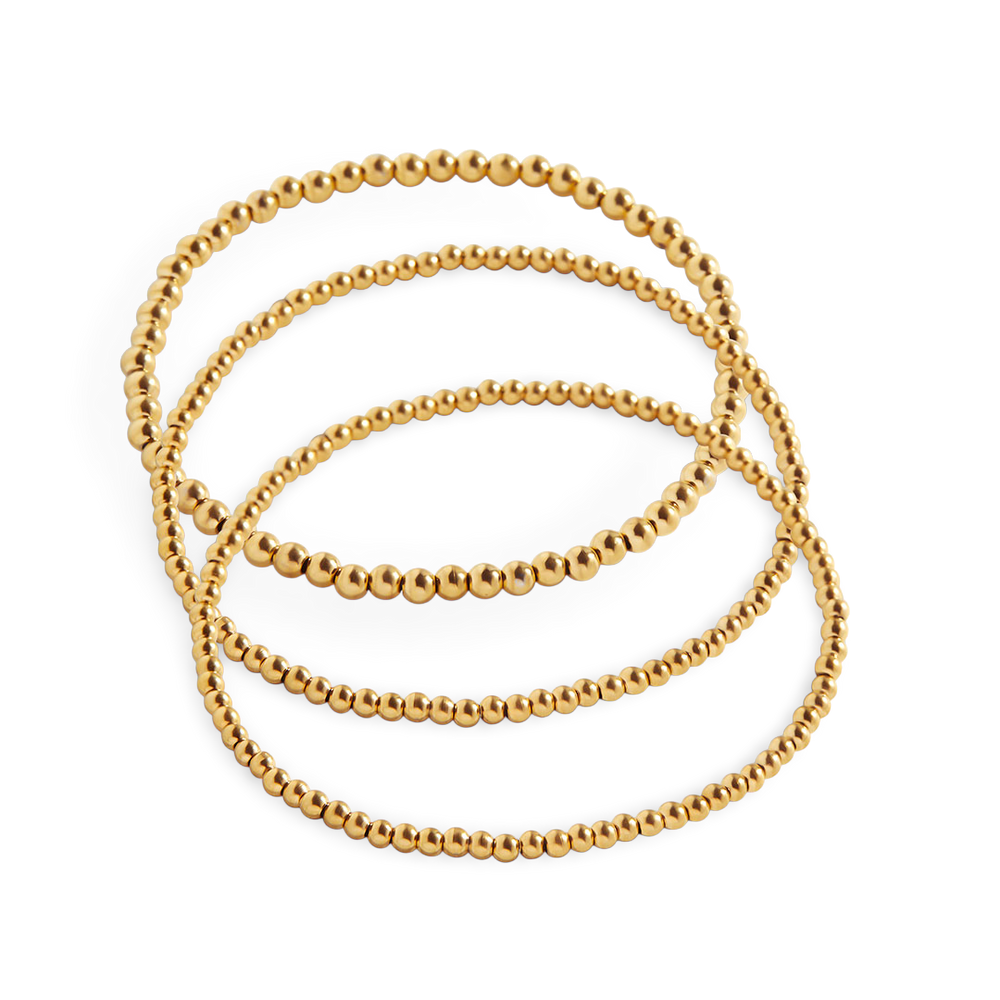 A set of gold-colored beaded bracelets stacked together.