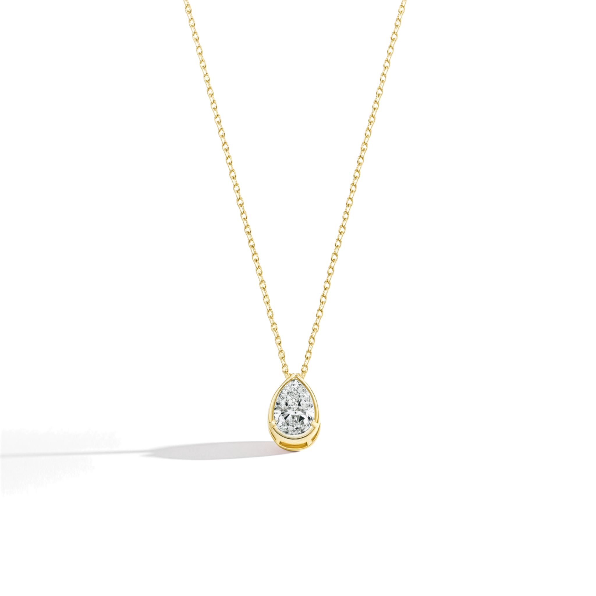 Gold necklace with a teardrop-shaped diamond pendant on a light beige background