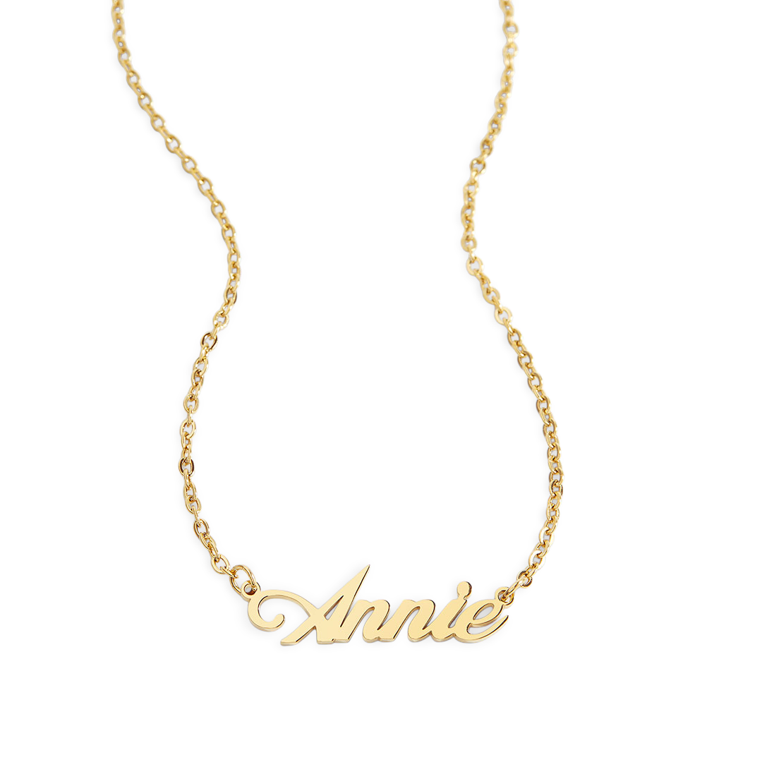 A gold name necklace with the name 'Annie' written in a cursive script on a chain.