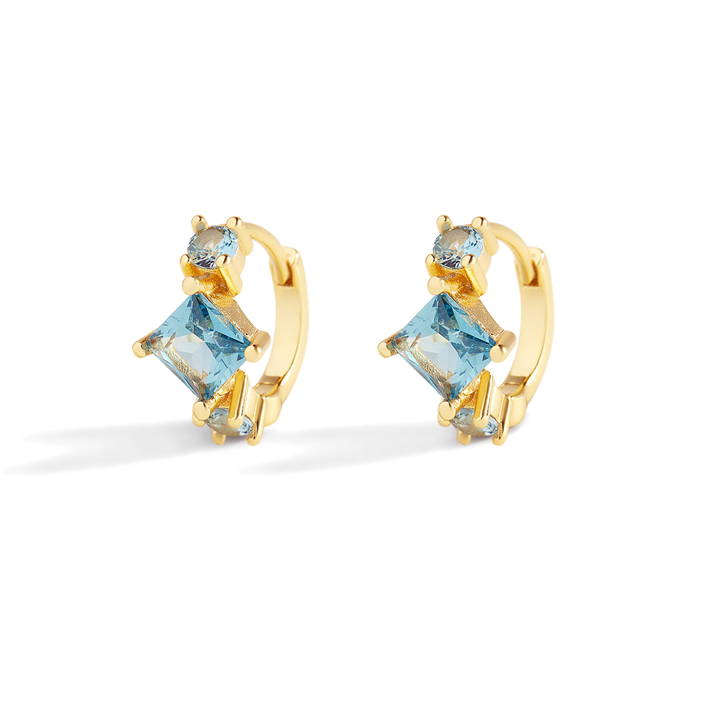 Gold hoop earrings with blue gemstones on a white background
