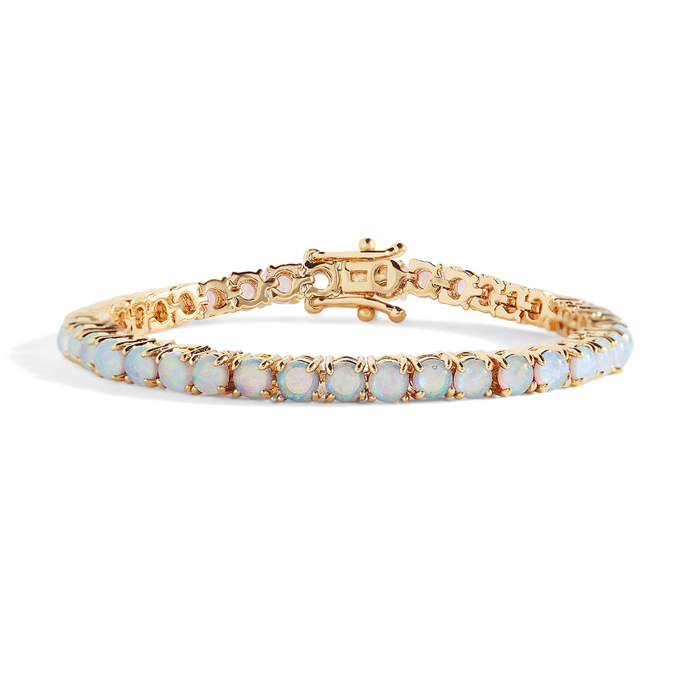 Gold bracelet with white stones on a light gray background
